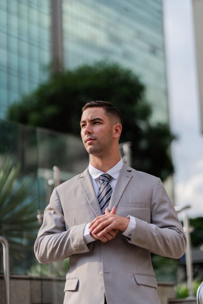Young businessman in a suit standing confidently outdoors in a city environment.
