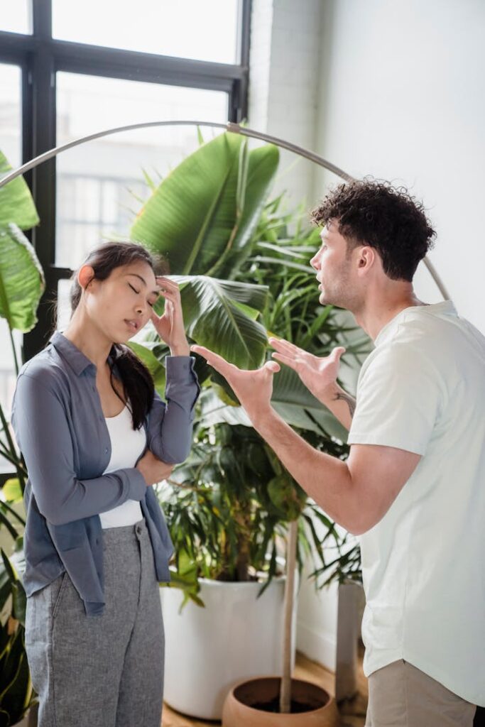 A man and woman having a heated argument indoors, surrounded by plants.